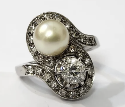Impresionante anillo fabricado en platino Diseño de los años 50 Con 1 diamante natural de aprox, 1 ct (6mm x 4.4mm) de color aprox. H 24 diamantes en talla brillante 1 perla cultivada Talla 20 Una joya impresionante